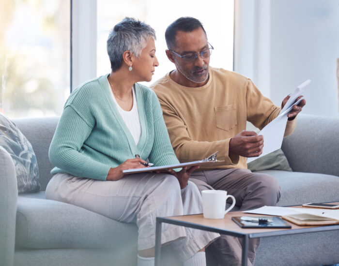 Finance, documents and senior couple on sofa with bills, paperwork and insurance checklist in home, life or asset management, Elderly black people on couch with financial, retirement or mortgage debt